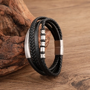 Macro detail of layered black braided leather bracelet with brushed steel magnetic clasp