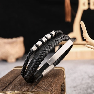 Detail of multi-layer black braided leather bracelet with silver steel beads and nameplate