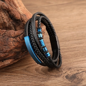 Detail of multi-layer braided leather bracelet with blue metal beads on wood