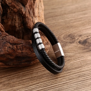 Detail of multi-layer braided black leather bracelet with silver metal beads and magnetic clasp
