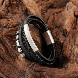 Men's multilayer braided black leather bracelet with matte silver metal plate on wood