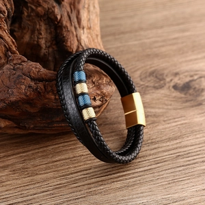 Detail of multilayer black leather bracelet with blue gold beads and magnetic clasp on wood