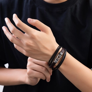 Detail of multi-layer black leather bracelet with red stitching and metal knot clasp