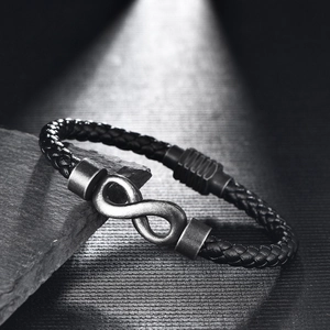 Close-up of black braided leather men's bracelet featuring a silver infinity charm