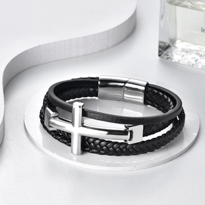 Detail of men's multilayer braided leather bracelet with silver steel cross and magnetic clasp