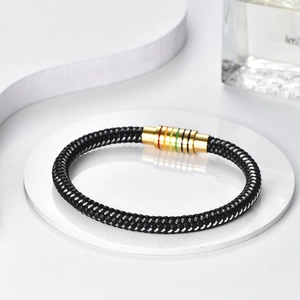 Detail of black braided leather bracelet featuring a gold magnetic clasp with rainbow rings