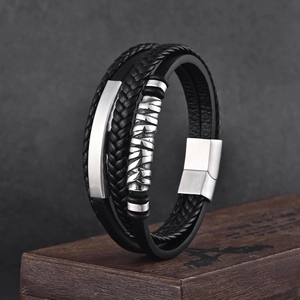 Détail d'un bracelet en cuir noir multicouche avec fermoir en métal sur boîte en bois vintage
