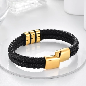 Detail shot of black braided leather bracelet with gold accents and secure metal clasp