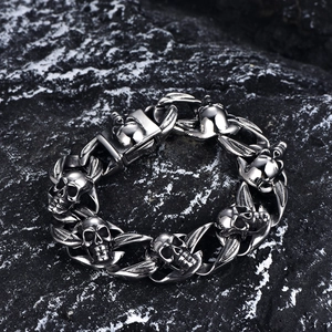 Detail shot of punk skull and feather link bracelet in vintage steel on dark rock