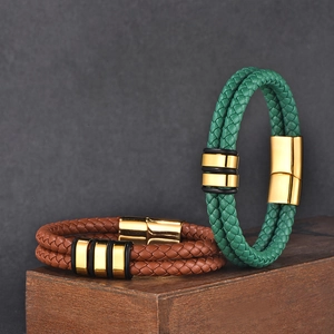 Detail showing braided leather bracelets with gold magnetic clasps on wood display