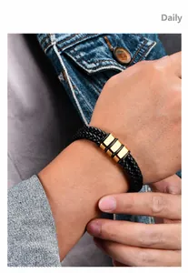 Close-up of men's black braided leather bracelet with golden charms on wrist