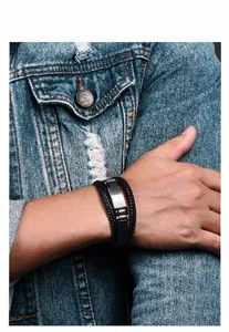Detail of multi-layer black braided leather bracelet with silver stainless steel plate on wrist