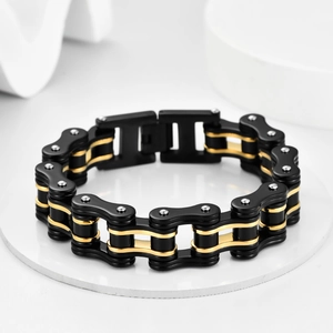 Detail of mechanical bicycle chain bracelet in black and gold stainless steel with rivets