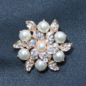 Elegant rose gold flower brooch with white pearls and sparkling rhinestones on leather