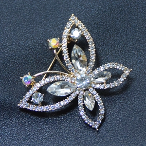 Broche papillon élégante en métal doré ornée de strass blancs et détails cristallins