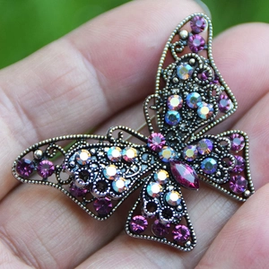 Dettaglio della spilla a farfalla vintage con strass viola e struttura in metallo