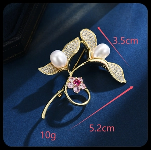 Detail view of a floral leaf brooch with pearls and zircon on a dark blue background