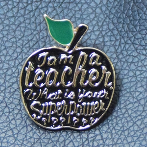 Detail of apple enamel brooch with I am a teacher What is your SuperPower quote