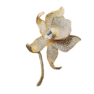 Elegant gold lily brooch with sparkling crystals and a water drop gemstone pendant