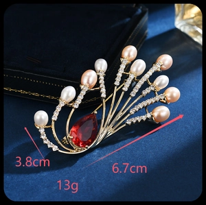 Detail view of peacock feather brooch with pearls and red gemstone, size 6.7cm x 3.8cm