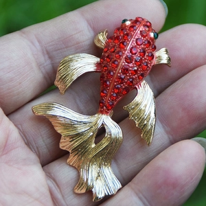 Vue macro de la broche poisson rouge avec strass rouges et détails ciselés des nageoires