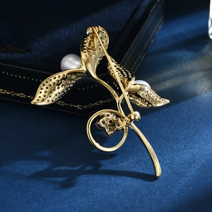 Elegant gold sprout brooch with white pearls and purple crystals on blue velvet
