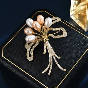 Elegant gold bouquet brooch with freshwater pearls and sparkling ribbon design detail