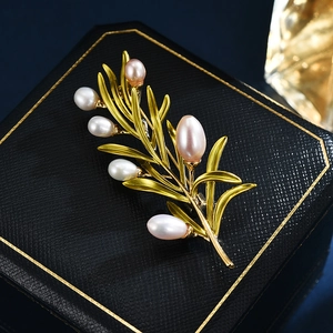 Elegant gold pine branch brooch with freshwater pearls on black jewelry box display