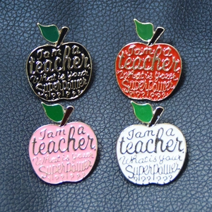 Cartoon apple teacher enamel brooches in four colors on dark leather background