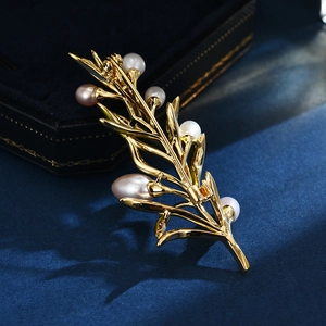 Elegant pine branch brooch in gold finish with freshwater pearls on navy velvet