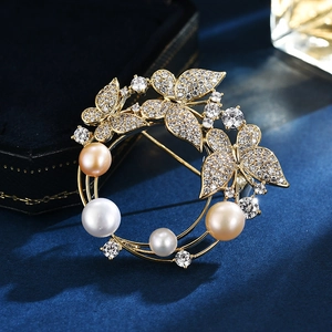 Exquisito broche de mariposa y perlas doradas con circonitas sobre fondo terciopelo