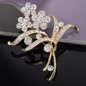 Elegante spilla a fiore dorata con strass di cristallo bianco su sfondo specchiato