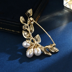 Leaf design gold brooch with freshwater pearls and secure pin clasp on blue background