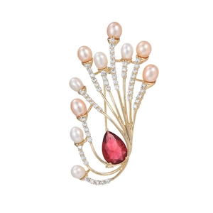 Elegant gold bow brooch with freshwater pearls and a large red teardrop gemstone