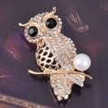 Elegant owl brooch pin with gold metal base, white rhinestones and a single pearl accent