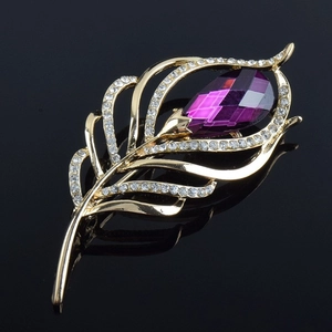 Vue détaillée d'une broche plume dorée avec cristal violet et strass blancs brillants