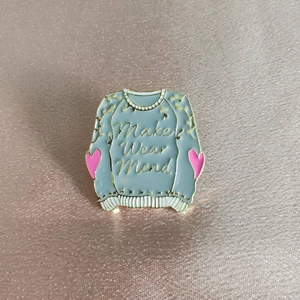 Broche pull en émail avec texte 'Make Wear Mend' et cœur rose sur fond bleu