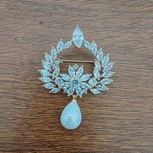 Elegant gold zircon pearl brooch with marquise stones and drop opal pendant on wood