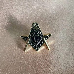 Detail of Freemasonry gold emblem with square and compasses on silk background