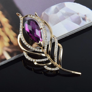 Détail de la broche plume dorée avec cristal goutte violet et strass étincelants