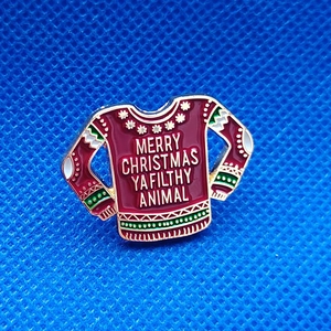 Detail of red enamel Christmas sweater brooch with Merry Christmas Ya Filthy Animal text