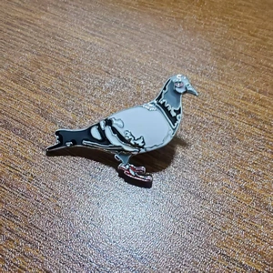 Detail of peace dove enamel brooch with silver metallic edges on wooden background