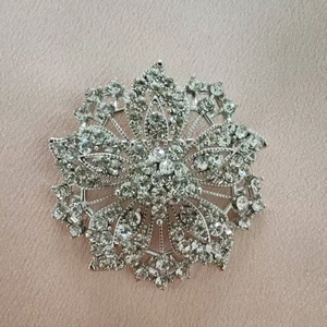 Broche flocon de neige argentée étincelante avec strass sur fond de tissu rose champagne