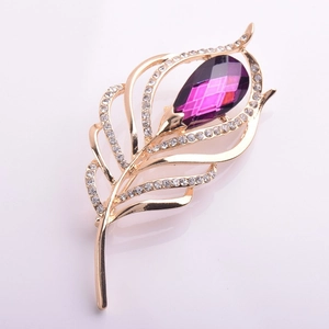 Vue détaillée d'une broche plume dorée avec gemme violette et strass brillants incrustés