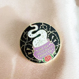Detail of round enamel brooch with purple cauldron and 'Only you can decide what breaks you' text