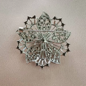 Élégante broche flocon de neige argentée avec cristaux sur fond de satin rose