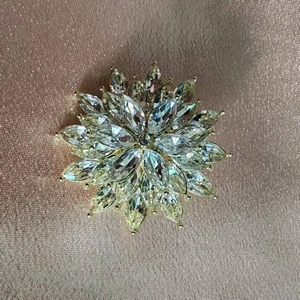 Détail d'une broche florale en cristal avec pierres taille marquise sur soie rose