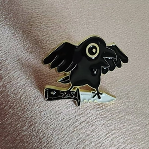 Gothic black crow enamel brooch perched on a white dagger with gold metal outlines