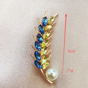 Detail view of a 6cm wheat brooch with blue and yellow crystals and a white pearl