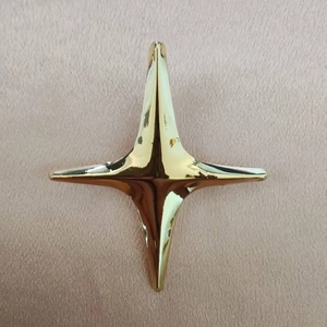 Vue rapprochée d'une broche étoile dorée à quatre branches avec finition miroir